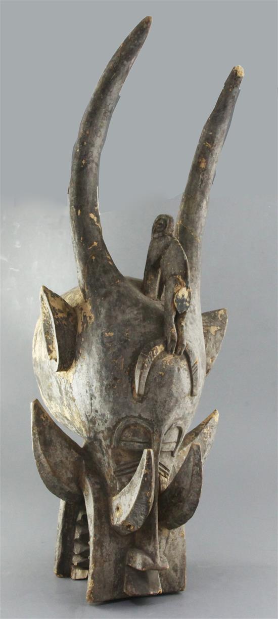 A Dogon carved wood mask with horns, tusks and teeth, height 81cm
